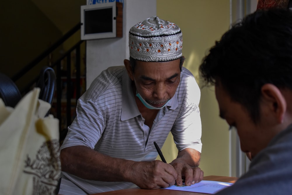 man in white and blue stripe button up shirt writing on white paper