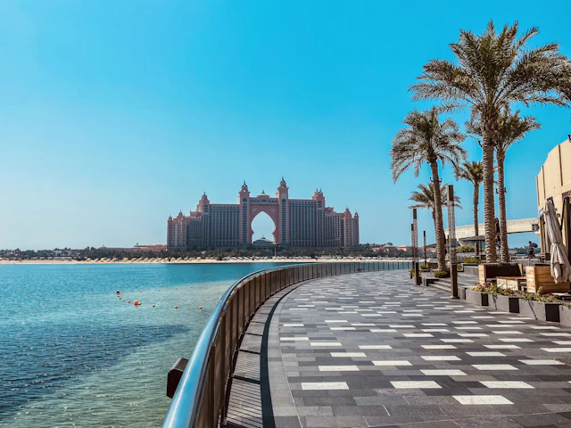 The pink arch of Atlantis The Palm seen across the lagoon from a palm-lined promenade on Palm Jumeirah.