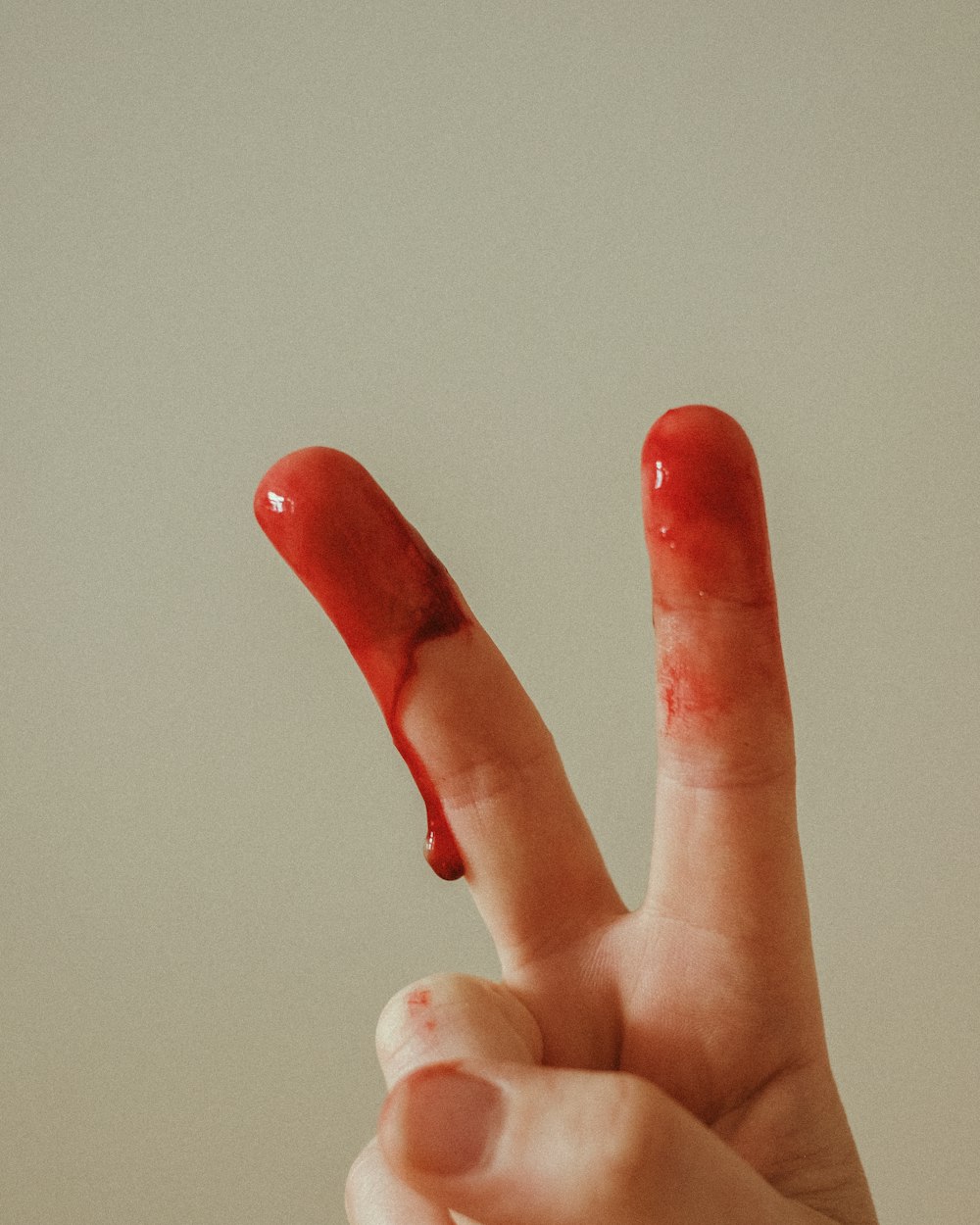 Persona con manicura roja haciendo el signo de la paz