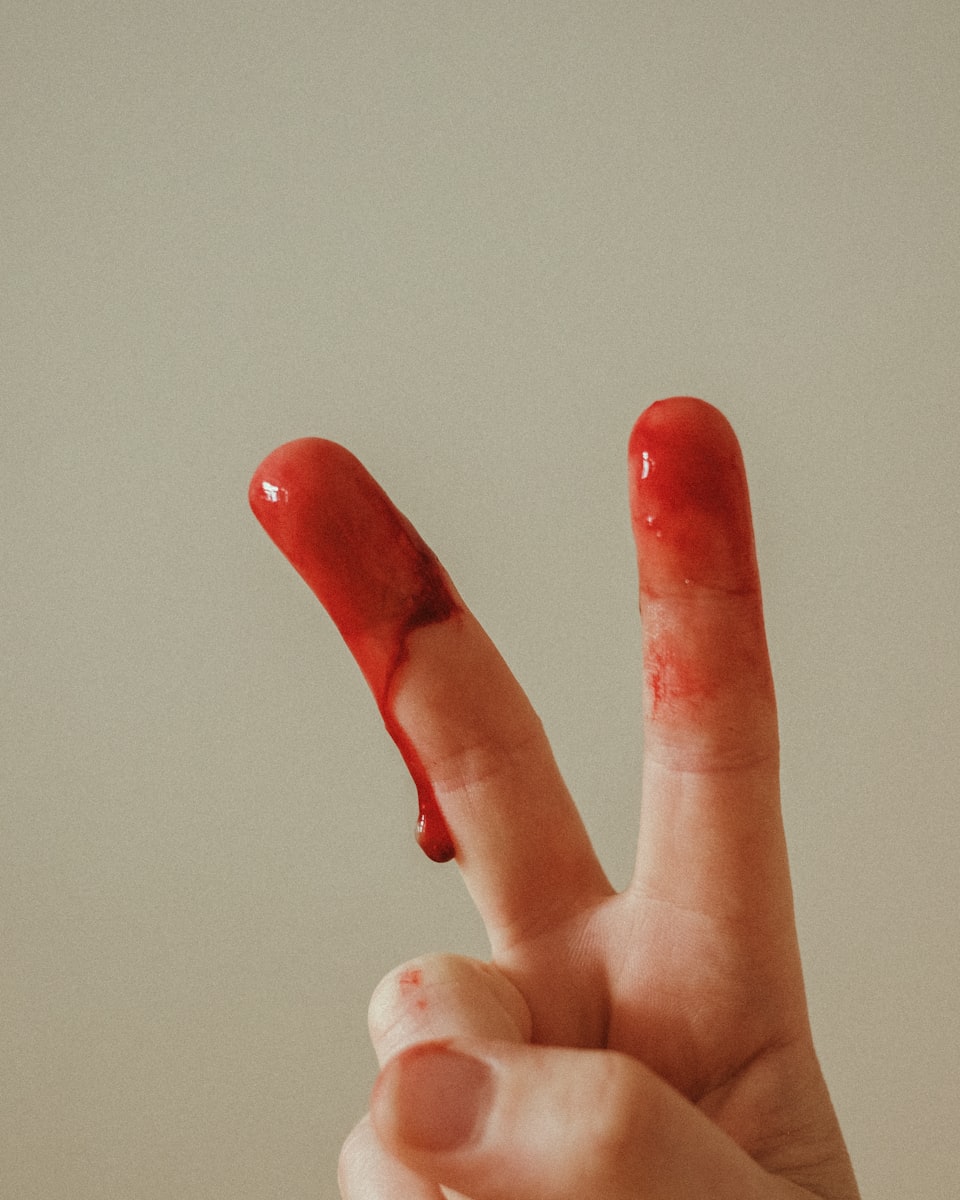 Two blood-covered fingers held up making the victory sign.