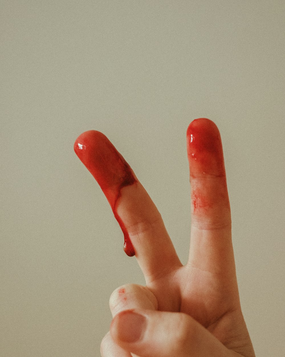 person with red manicure doing peace sign