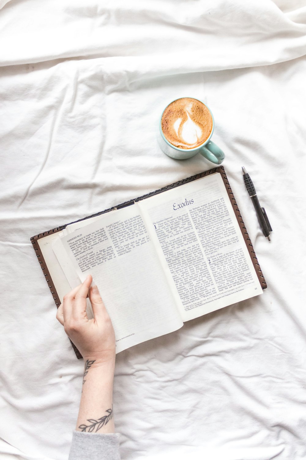 person reading book on white textile