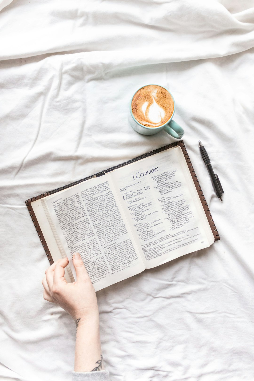 person reading book on white textile