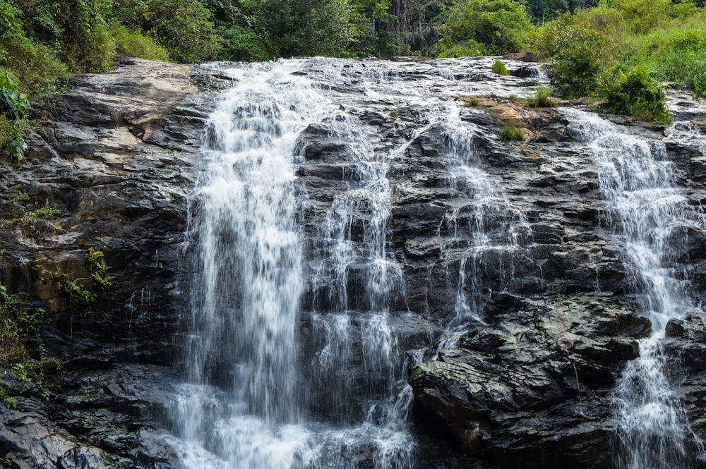 water falls on brown rocky mountain during daytime