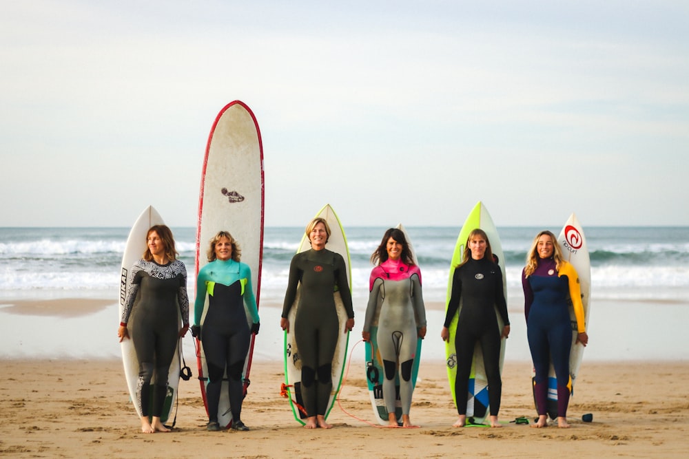 gruppo di donne che indossano camicia a maniche lunghe nere e verdi e pantaloni neri che tengono bianco e