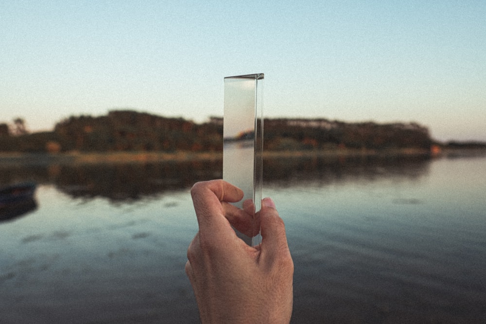 personne tenant une tasse en verre transparent