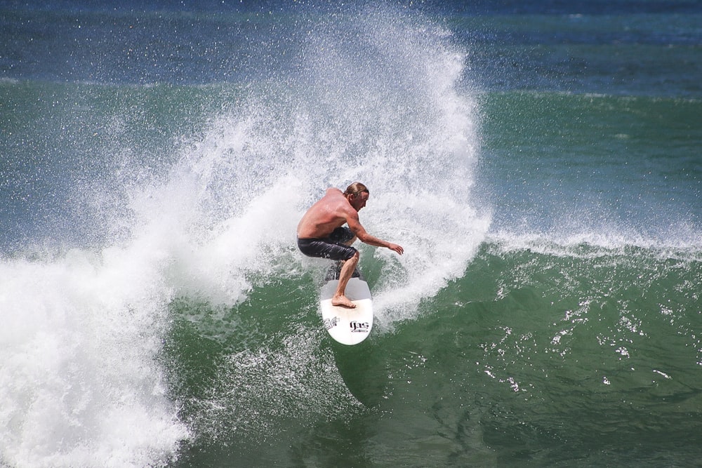 man in black shorts surfing on sea waves during daytime