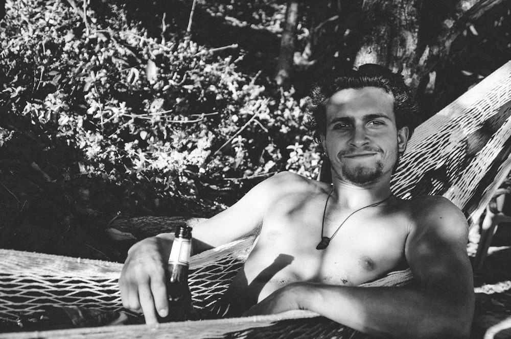 topless man holding bottle and glass bottle in grayscale photography