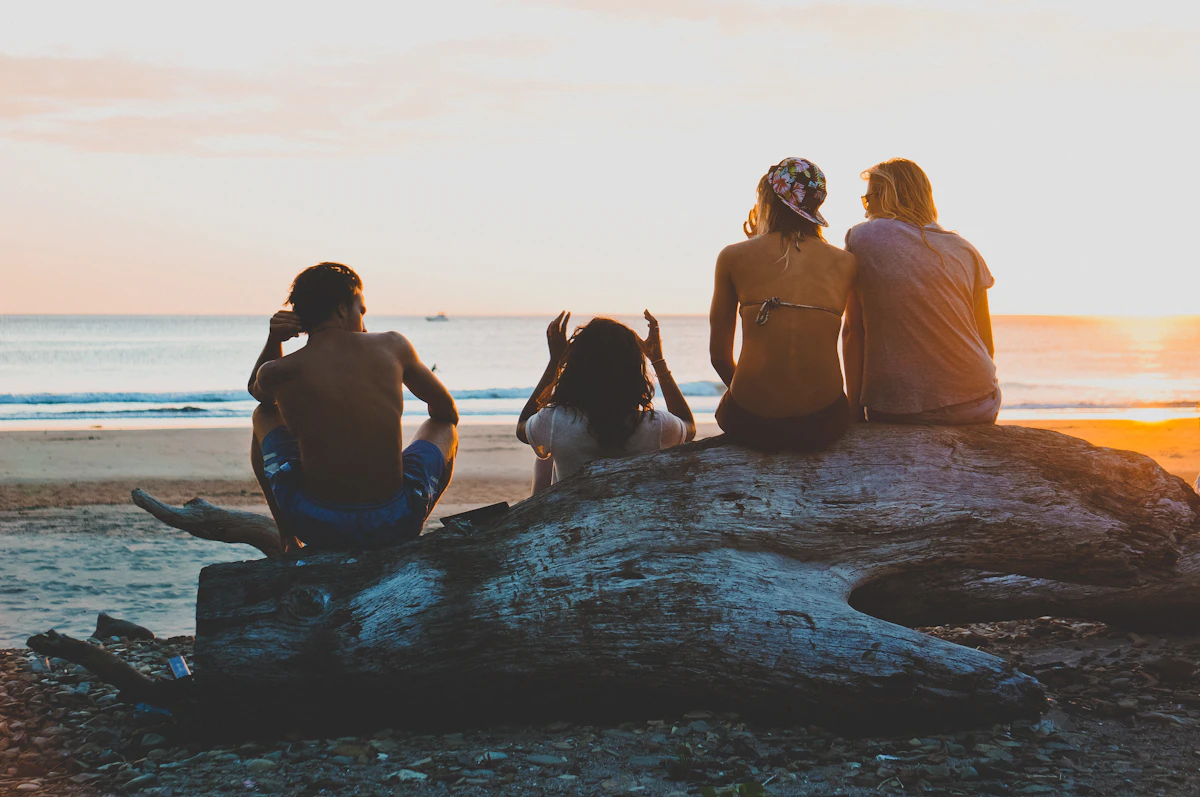 Friends sitting on rocks watching the sun set over the sea
