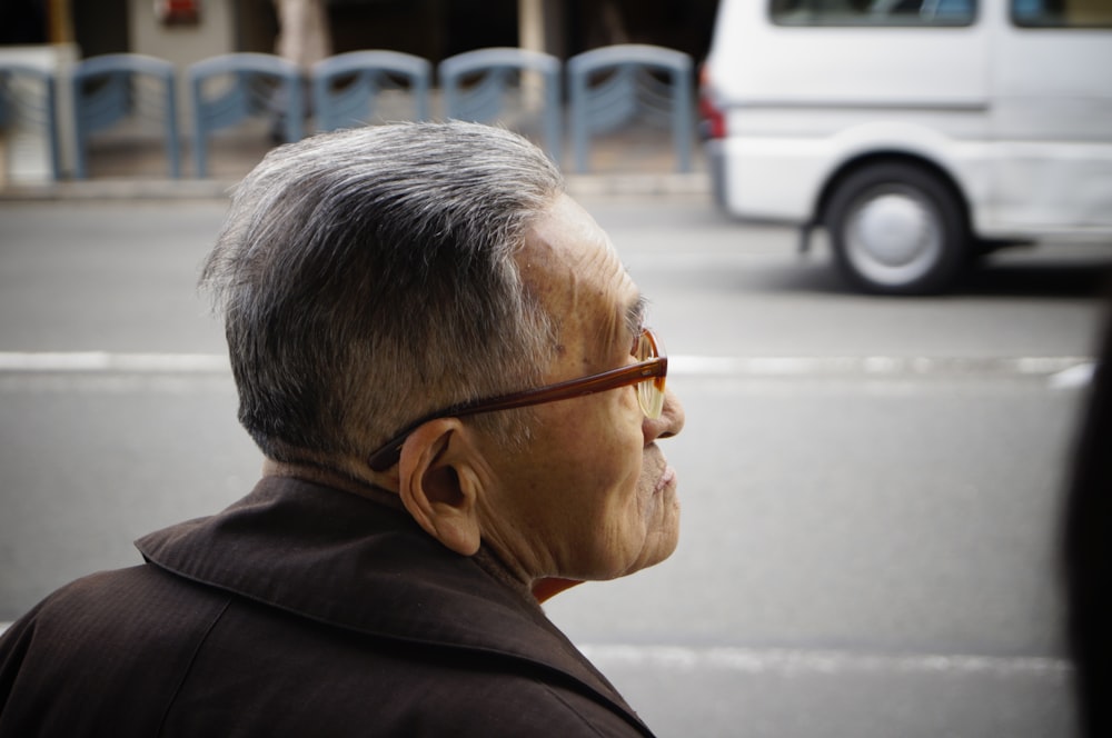 man in black coat wearing brown framed eyeglasses