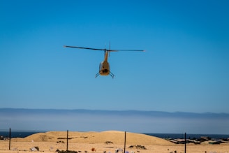 A helicopter flying over open terrain during daytime.