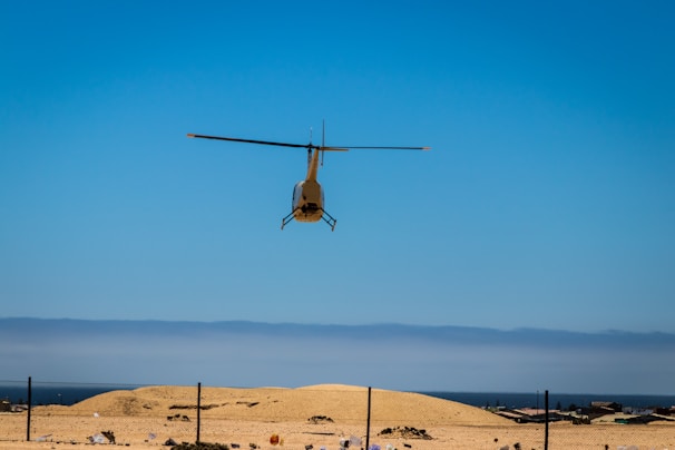 A helicopter flying over open terrain during daytime.