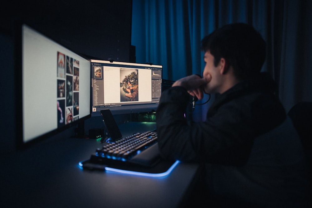 Mann in schwarzem Kapuzenpulli sitzt vor dem Computer