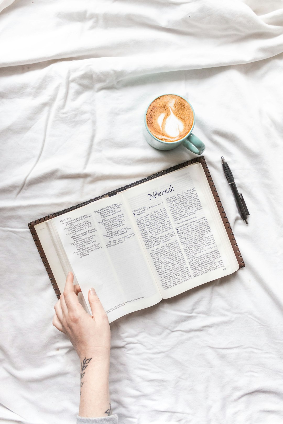 person reading book on white textile