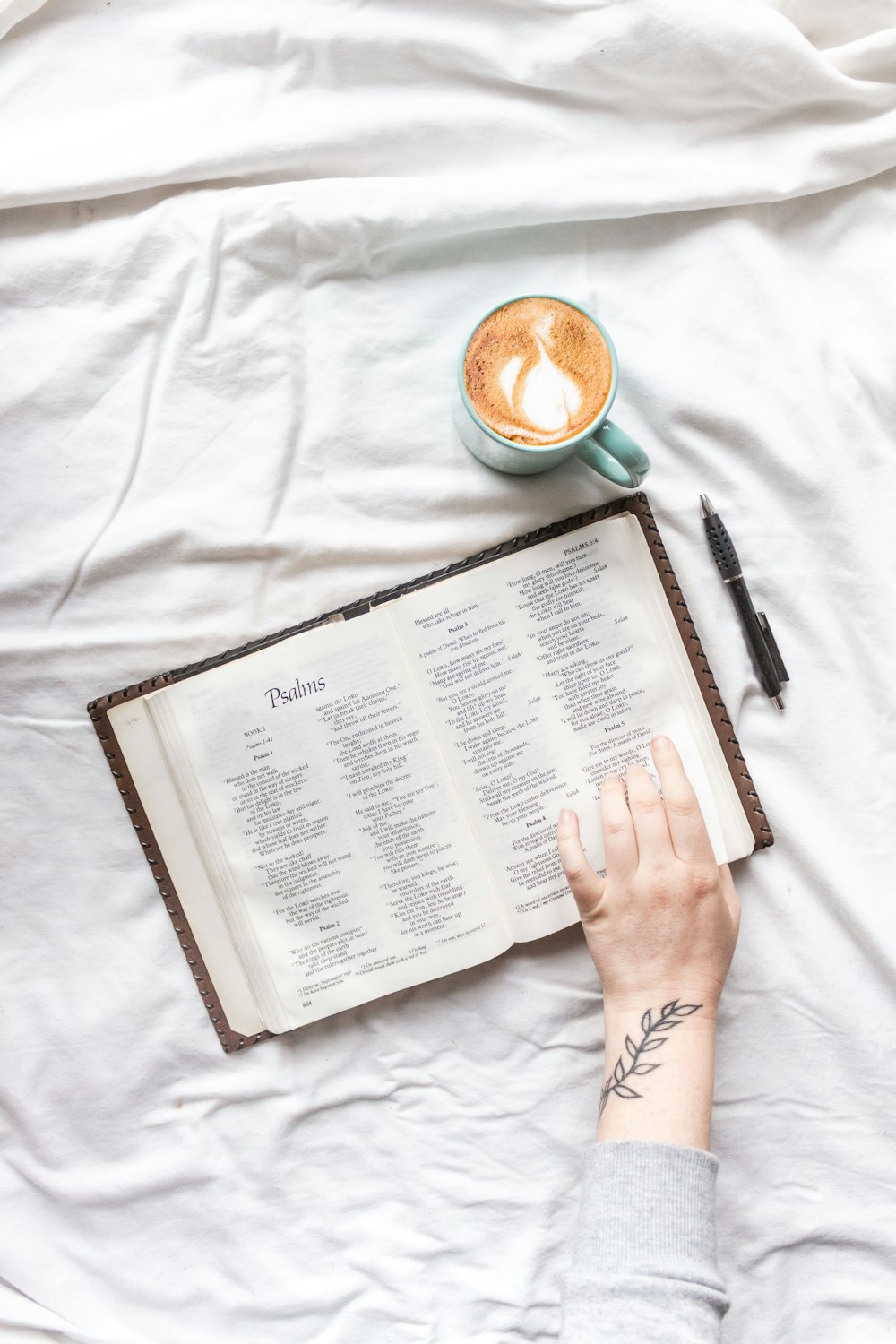 person reading book on white textile