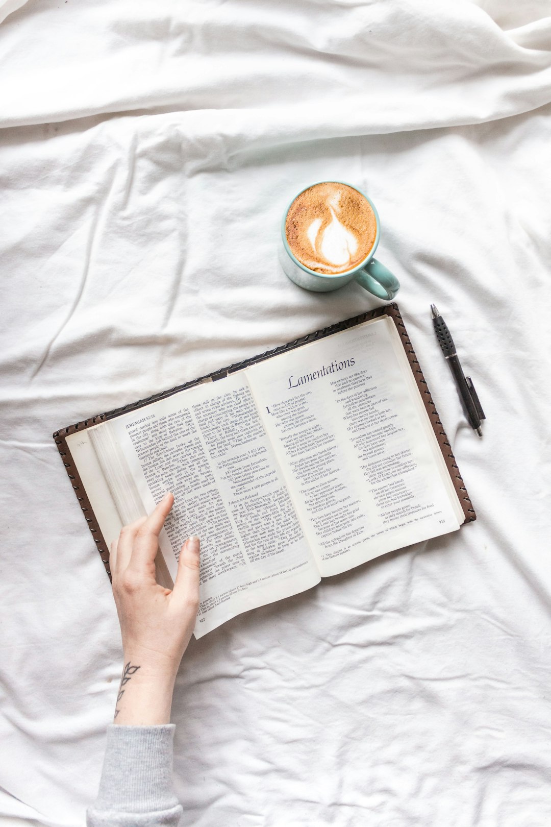 person reading book on white textile