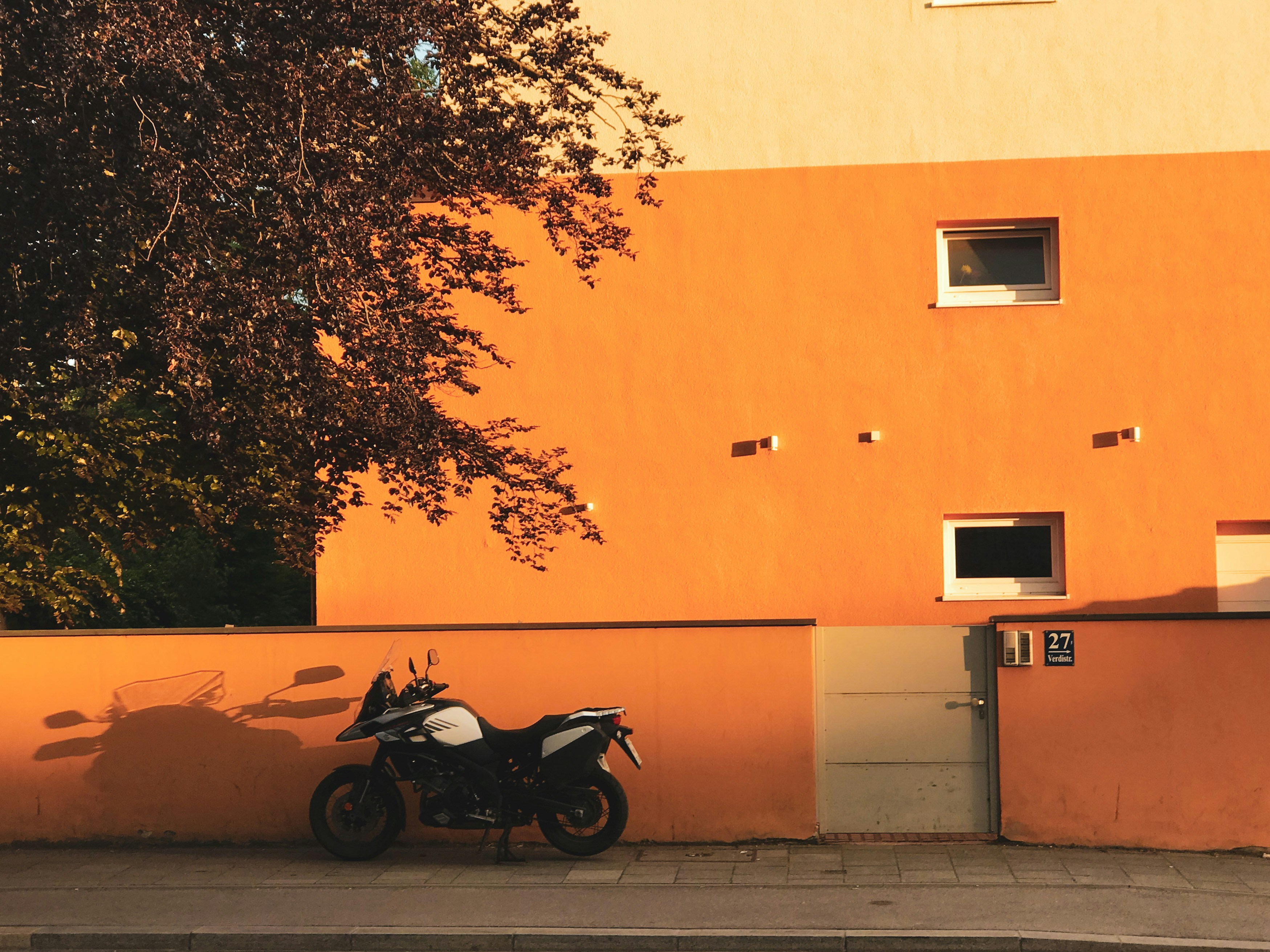 black motorcycle parked beside orange concrete wall