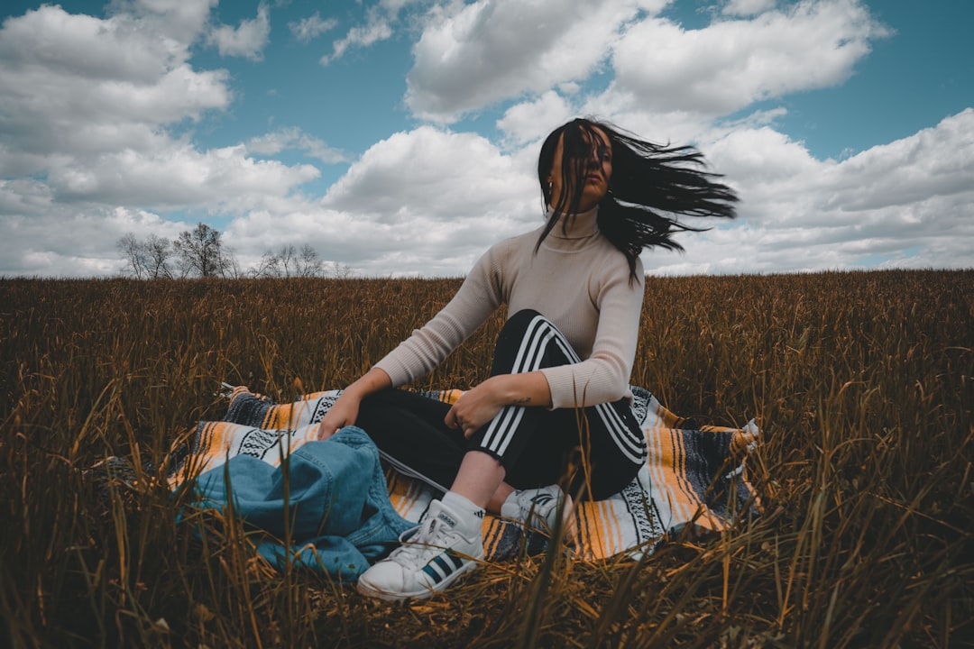 woman in white long sleeve shirt sitting on chair on brown grass field during daytime