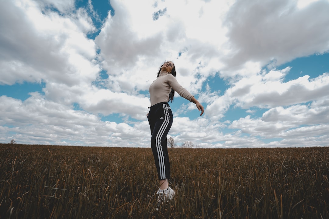 woman in black and white stripe skirt standing on brown grass field under blue and white