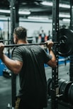 man in black t-shirt carrying barbell