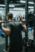 A trainer demonstrating proper form for a squat in a gym setting.