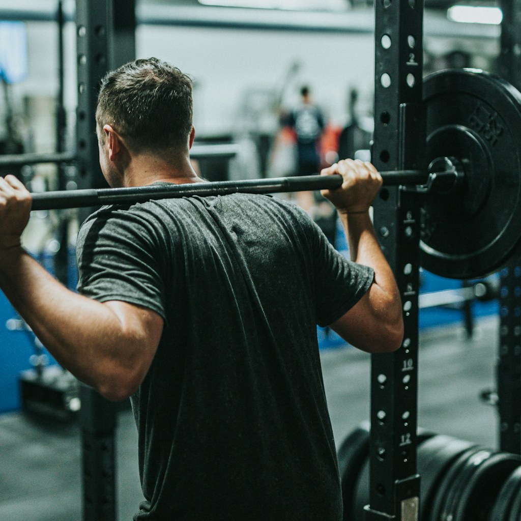 man in black t-shirt carrying barbell