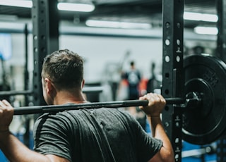 man in black t-shirt carrying barbell