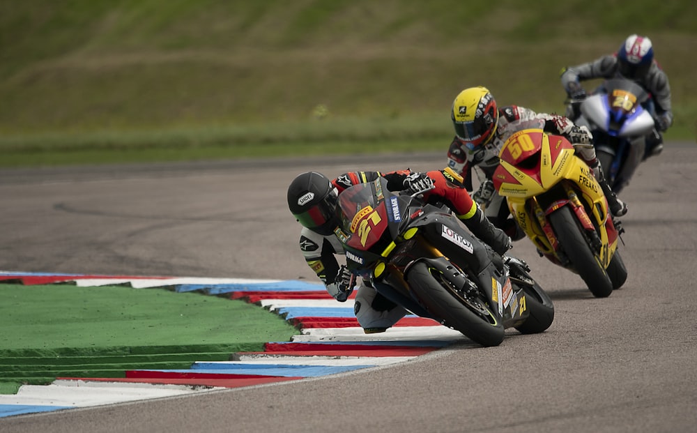 man in yellow and black racing suit riding on orange and green sports bike