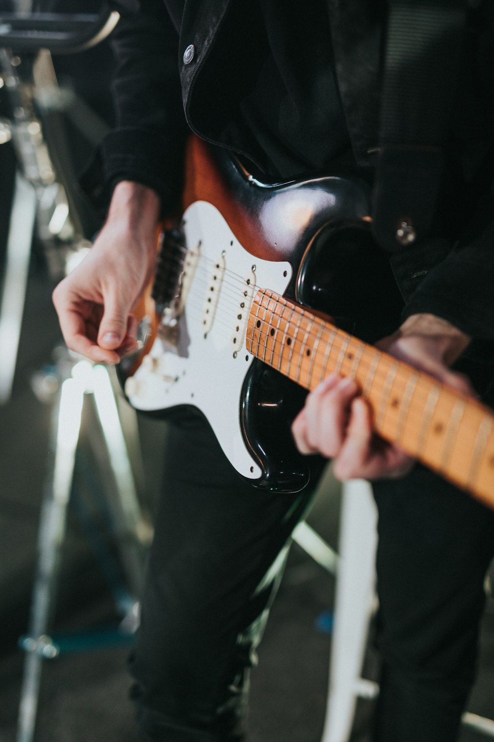 Persona tocando la guitarra eléctrica Stratocaster blanca y marrón