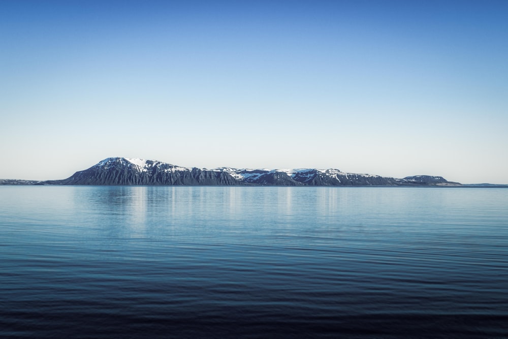 body of water near mountain during daytime