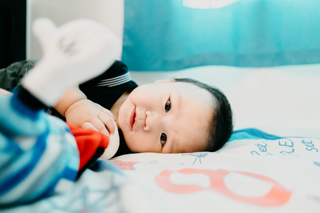 baby in black and white shirt lying on bed