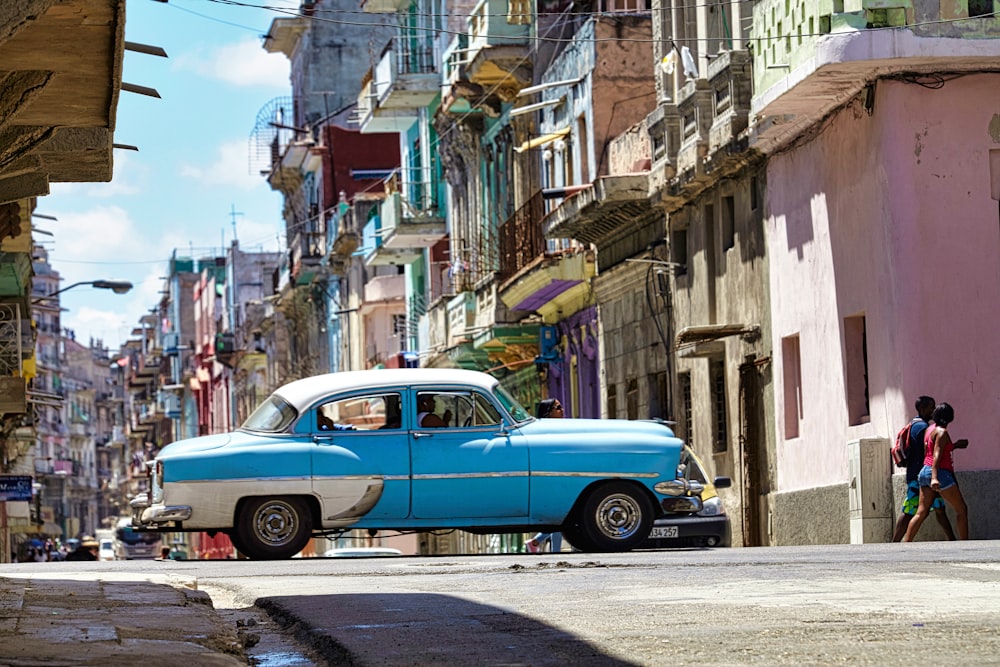 Voiture classique bleue garée à côté de l’immeuble pendant la journée