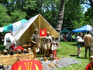 A detailed Roman military camp bustling with legionnaires preparing for battle under a fiery sunset.