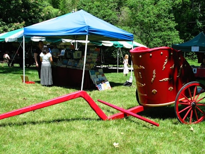 An outdoor literary event with attendees browsing books and chatting under trees.