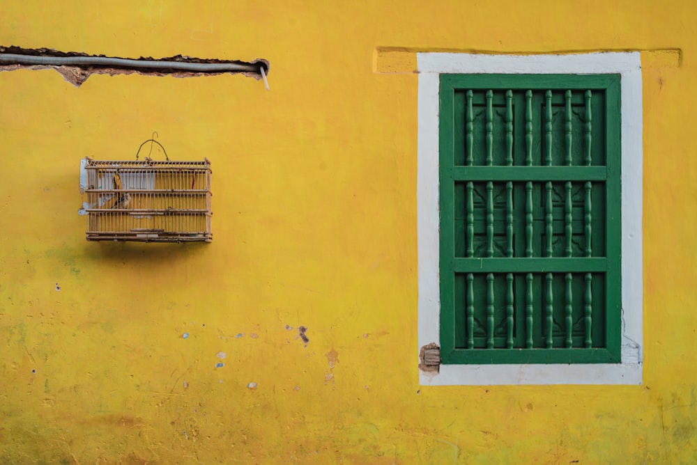green wooden window frame on yellow concrete wall