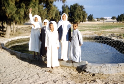 man in white thobe standing beside woman in white dress kuwait zoom background