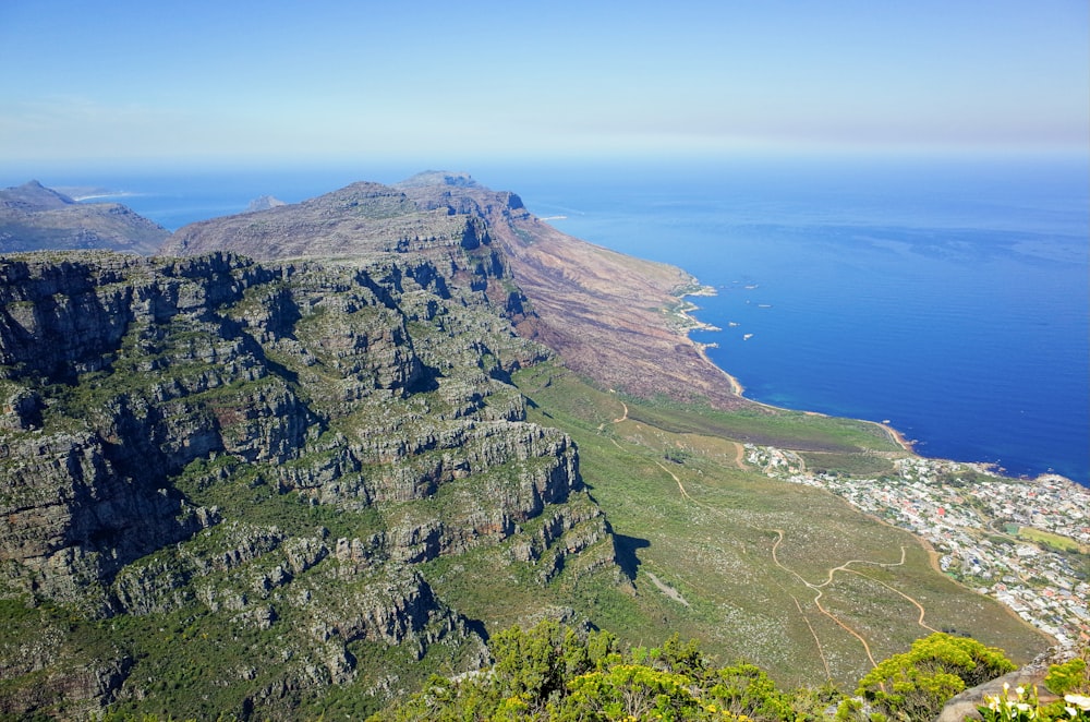 green and brown mountain beside blue sea under blue sky during daytime