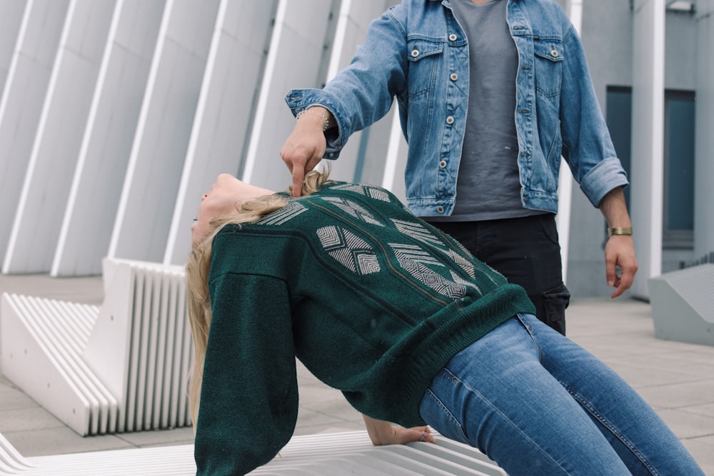 person in blue denim jacket and blue denim jeans sitting on white wooden bench