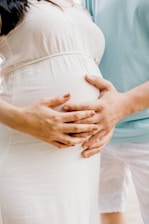 Two people gently place their hands on a pregnant belly, symbolizing love and anticipation. The scene exudes warmth and tenderness.
