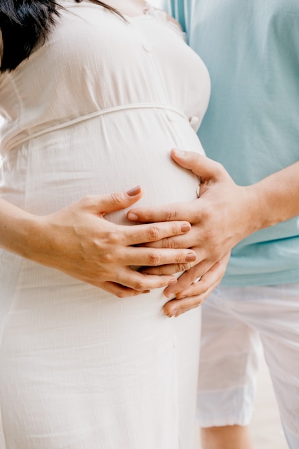 Close-up of hands of a father and pregnant partner joined together over her belly, symbolizing unity and anticipation.