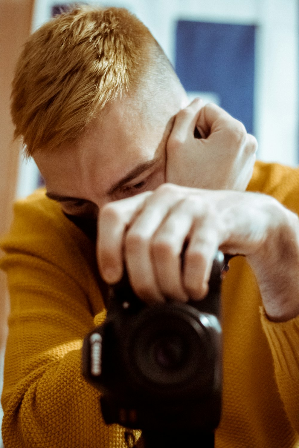 man in yellow sweater holding black nikon dslr camera