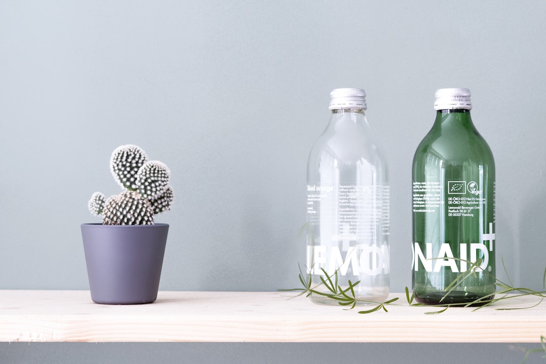 green glass bottle beside blue ceramic cup