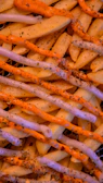 Close-up of a plate with crispy Dutch fries and a frikandel served with sauces on a wooden table.