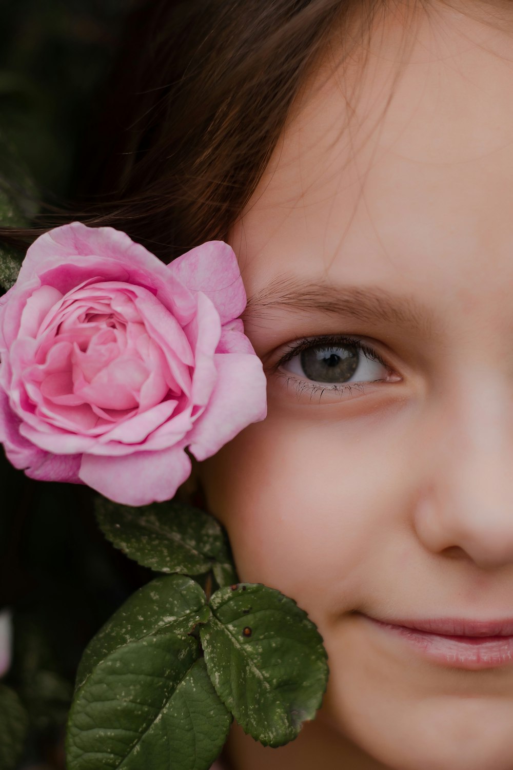 girl holding pink rose in close up photography