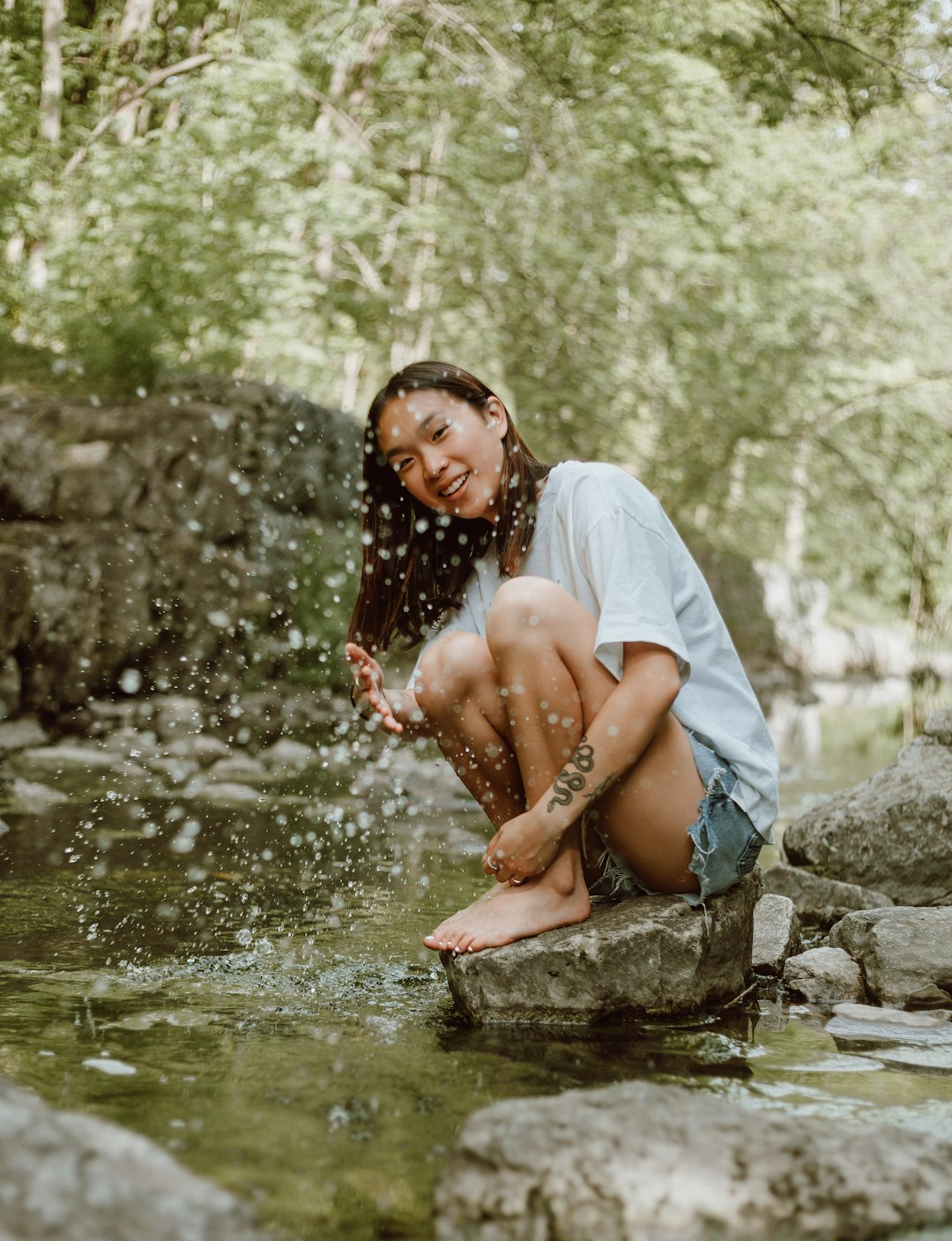 woman in white shirt sitting on rock near river during daytime