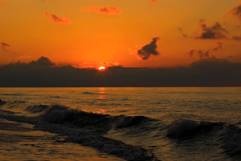 ocean waves under orange sky during sunset