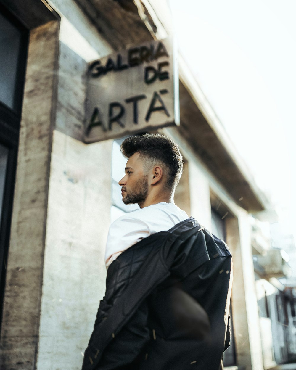 Hombre con camisa blanca y pantalones negros sentado en una pared de hormigón durante el día