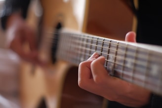 person playing brown acoustic guitar