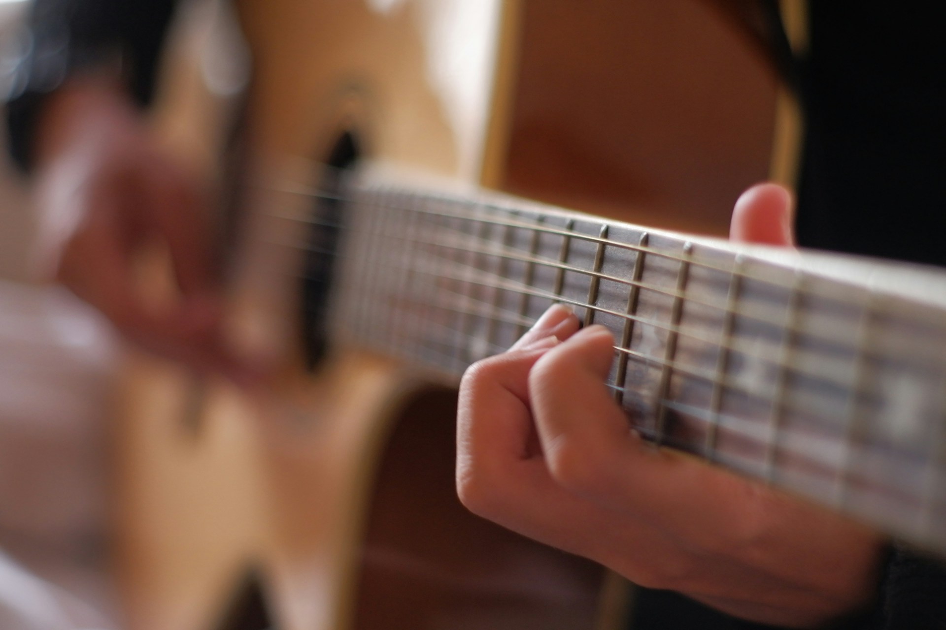person playing brown acoustic guitar