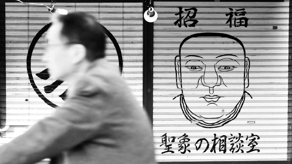 man in gray coat standing beside window